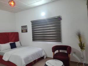 a bedroom with a bed and a chair and a window at G Spot Hotel in Port Harcourt
