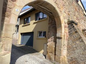 a building with an archway next to a stone wall at Studio vieille porte in Hombourg-Haut