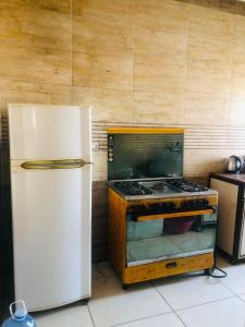 a kitchen with a stove and a white refrigerator at نورس هوم in Al Ghuşnah