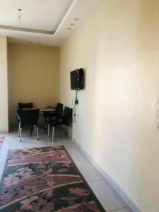 a room with a table and chairs and a tv on a wall at نورس هوم in Al Ghuşnah
