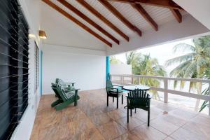 a patio with chairs and a table and a balcony at Condo #31 @ Beachside Villas in Placencia