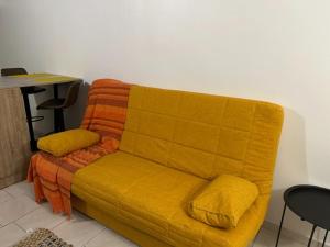 a yellow couch in a room with a table at Studio Relais Les Abymes in Les Abymes