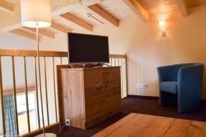 ein Wohnzimmer mit einem TV und einem blauen Stuhl in der Unterkunft Hotel Forelle in Plansee