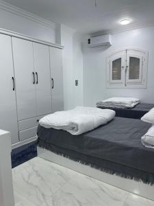 two beds in a room with white walls and white cabinets at Chez Cat & Lolo in Quseir