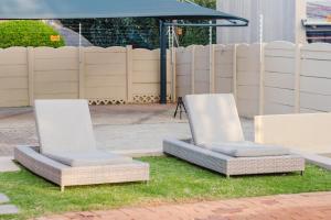 two chairs sitting on the grass under an umbrella at Edenvale corner in Edenvale