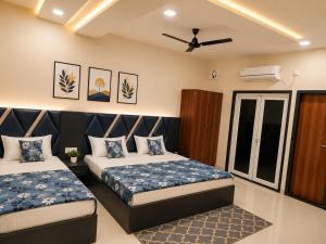 a bedroom with two beds and a ceiling fan at Hotel Atlas in Raigarh
