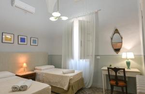 a room with two beds and a table and a mirror at Dimora San Vito in Lequile