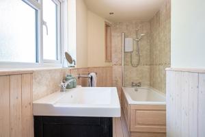 a bathroom with a white sink and a bath tub at Primrose Spinney in Ringwood +48 photos