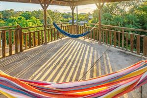 a hammock on a deck with a view of trees at 2 Coco Locos at Sunset in Seine Bight Village