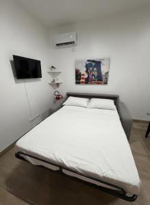a white bed in a room with a tv at Enjoy and Fly, NEAR THE AIRPORT AND THE SEA in Fiumicino