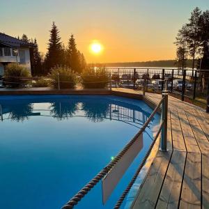 a swimming pool with a sunset in the background at Aateli Lakeside Chalets - former Vuokatti Suites in Vuokatti