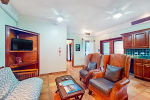 a living room with chairs and a tv and a table at Condo #25 @ Beachside Villas in Placencia
