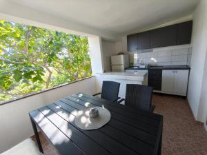 a kitchen with a table and chairs and a window at Apartments Šešo C in Pag