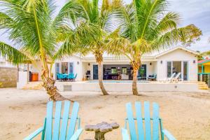 two blue chairs on the beach with palm trees at Tres Palmas Beach House in Maya Beach