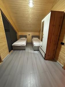two beds in a room with a wooden floor at MMED SWEET HOMe in Bosteri +2 photos