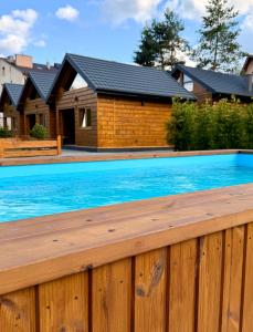 a wooden fence with a swimming pool in front of a house at Pod Bieszczadzkim Niebem in Lutowiska