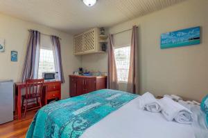 a bedroom with a bed and a desk and window at DV #1 at DV Cabanas - Gold Standard Certified in Caye Caulker
