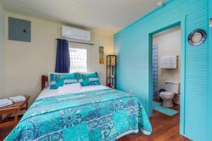 a blue bedroom with a bed and a toilet at DV #1 at DV Cabanas - Gold Standard Certified in Caye Caulker