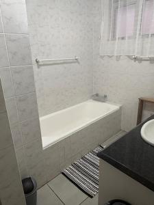 a white bathroom with a tub and a sink at Oceans Whisper 704 beach apartment gated & Lift access in Scottburgh +26 photos