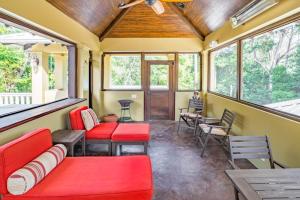 a screened in porch with red furniture and windows at The Reserve in Dangriga