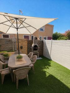 a patio with a table and chairs with an umbrella at Maison village accès mer et commerces à pieds in Le Barcarès