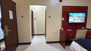 a room with a tv and a bedroom with a bed at The Carlisle Hotel LTD in Asaba