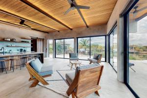a living room with a ceiling fan and some chairs at Seabird - Villa 26 in Placencia