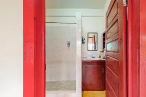 a bathroom with a shower and a red door at Palmetto#1 @ Island Cabanas in Caye Caulker