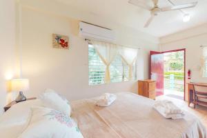 a bedroom with a large white bed and a window at Palmetto#1 @ Island Cabanas in Caye Caulker