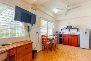 a kitchen with a table and a tv in a room at Palmetto#1 @ Island Cabanas in Caye Caulker
