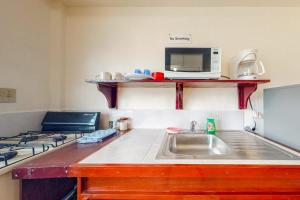 a kitchen with a sink and a microwave at Palmetto#1 @ Island Cabanas in Caye Caulker +7 photos