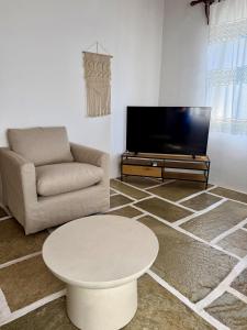 a living room with a couch and a table and a tv at Villa Ambelas - Traditional House in Ambelas