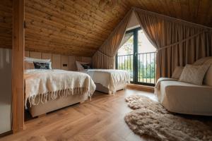 two beds and a couch in a room with wooden ceilings at Sploty Lasu u stóp Lubonia - Domki z Jacuzzi in Rabka-Zdrój