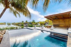 a swimming pool with chairs and a house at Seabird Villa 11 in Placencia
