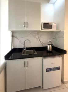 a white kitchen with a sink and a microwave at Palm Dorms in Beirut