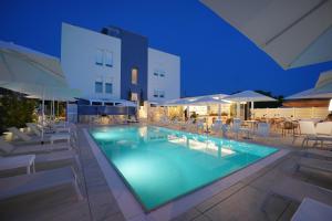 a swimming pool with chairs and umbrellas at night at Hotel Mhami in Pulsano