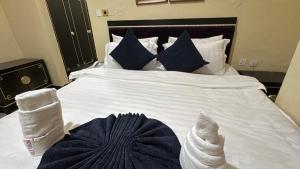 a bed with blue and white sheets and blue pillows at The Carlisle Hotel LTD in Asaba +1 photo