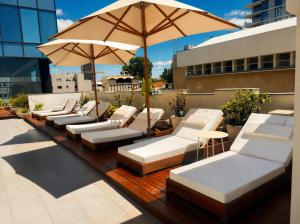 a row of white lounge chairs and an umbrella on a rooftop at Hotel Rothschild 22 - FATTAL COLORS in Tel Aviv