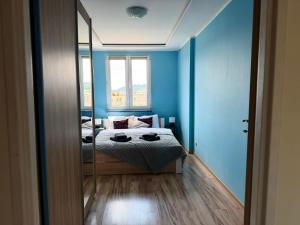 a bedroom with blue walls and a bed with a mirror at Apartament Sudeckie Kamyki in Głuszyca