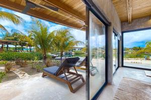a chair on a patio with a view of the beach at Seabird - Villa 1 in Placencia