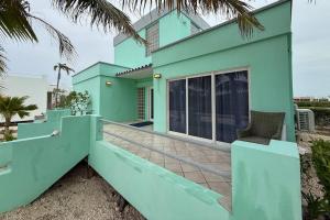 a blue house with a balcony with a chair at Villa 18 at Maralaguna in San Pedro