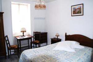 a bedroom with a bed and two chairs and a table at Le Fenelon in Carennac