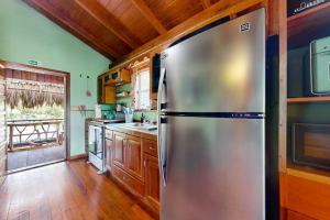 a stainless steel refrigerator in a kitchen with wooden floors at Bungalow Bobo in Placencia +27 photos