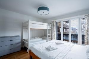 a bedroom with a white bunk bed and a window at La Riva mit Berg- und Seeblick in Laax