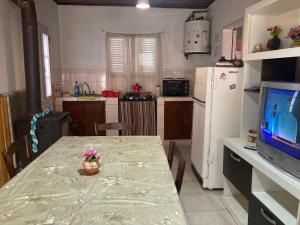 a kitchen with a table and a refrigerator and a television at La casita in Pringles