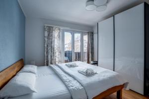 a bedroom with a large white bed with a window at La Riva mit Berg- und Seeblick in Laax