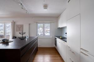 a kitchen with white cabinets and a black counter top at La Riva mit Berg- und Seeblick in Laax