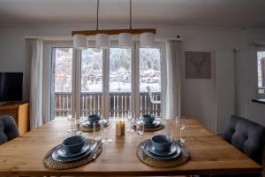 a dining room with a wooden table with dishes on it at La Riva mit Berg- und Seeblick in Laax +27 photos