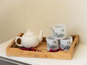 a wooden tray with three cups and a tea pot at Hoeve Tramzicht in Hellevoetsluis