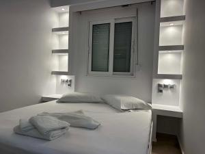 a white bed with two pillows and a window at Bazakos Luxury Kampi Beach Studio 2 in Fournoi